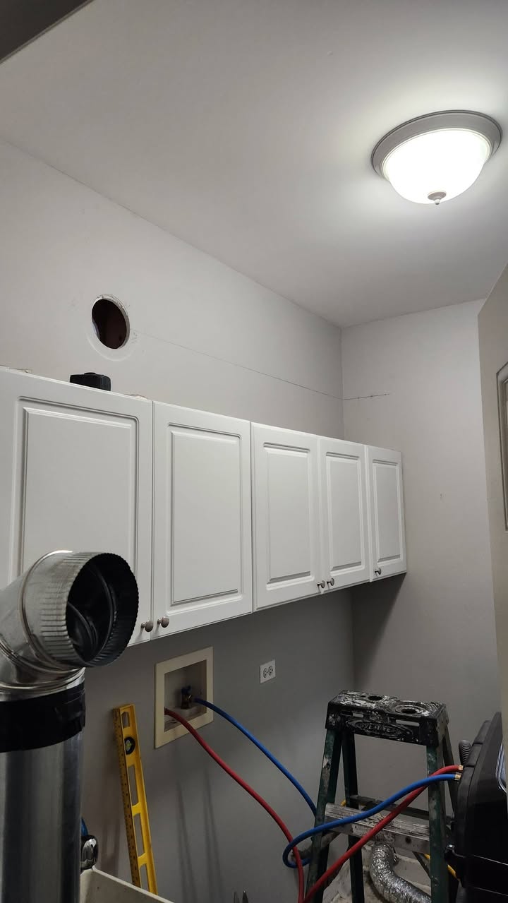 The same laundry room partway through the project, with cabinets painted and the walls being finished.